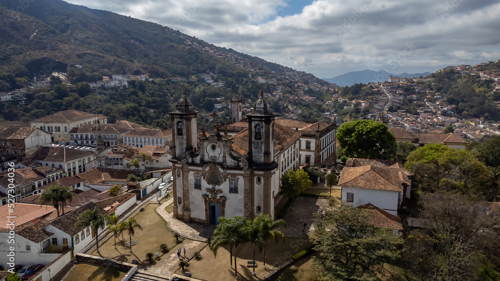 Visão panoramica de igreja em cidade histórica de Ouro Preto Minas Gerais em meio a montanhas e céu nublado construções e casas antigas ao fundo